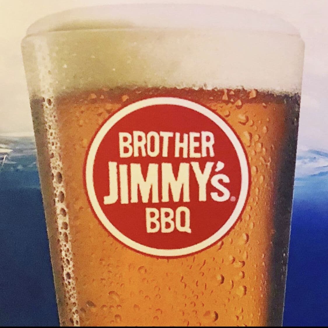 An ice-cold pint glass with the red Brother Jimmy's BBQ logo