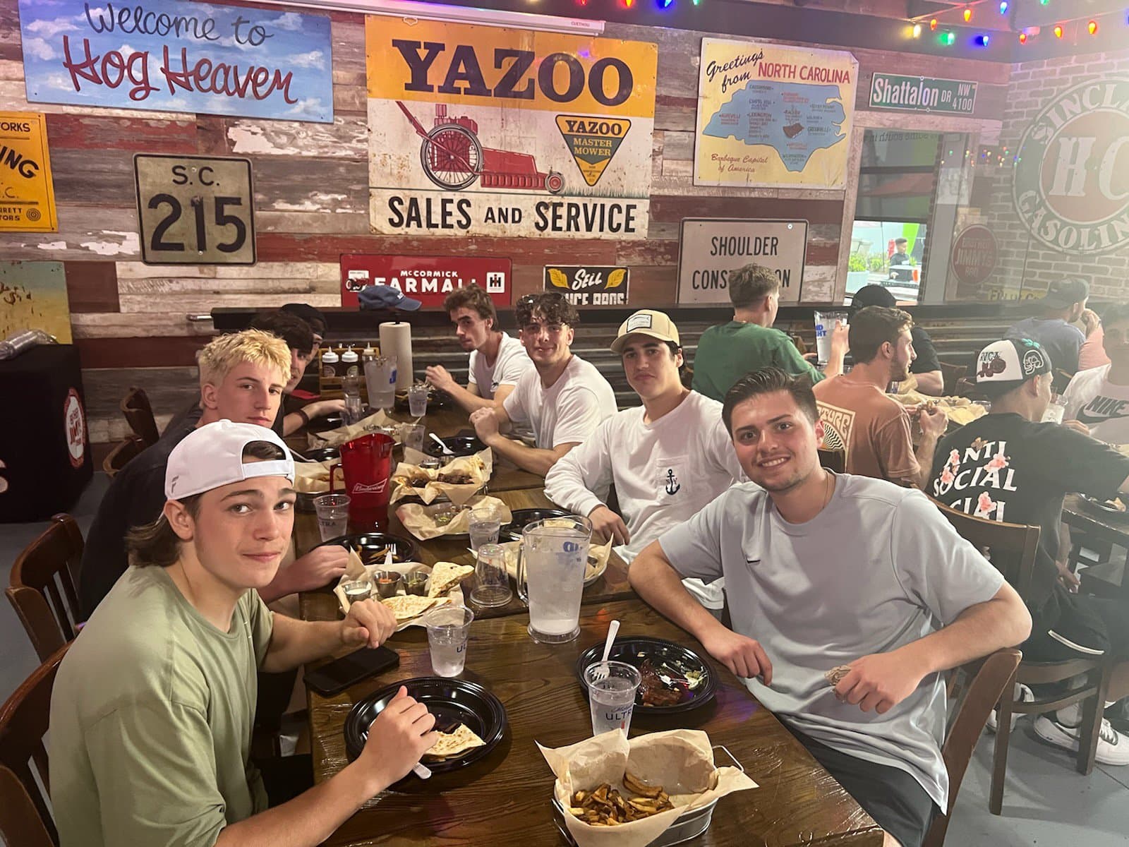 A table of friends mid-feast under the Welcome to Hog Heaven sign