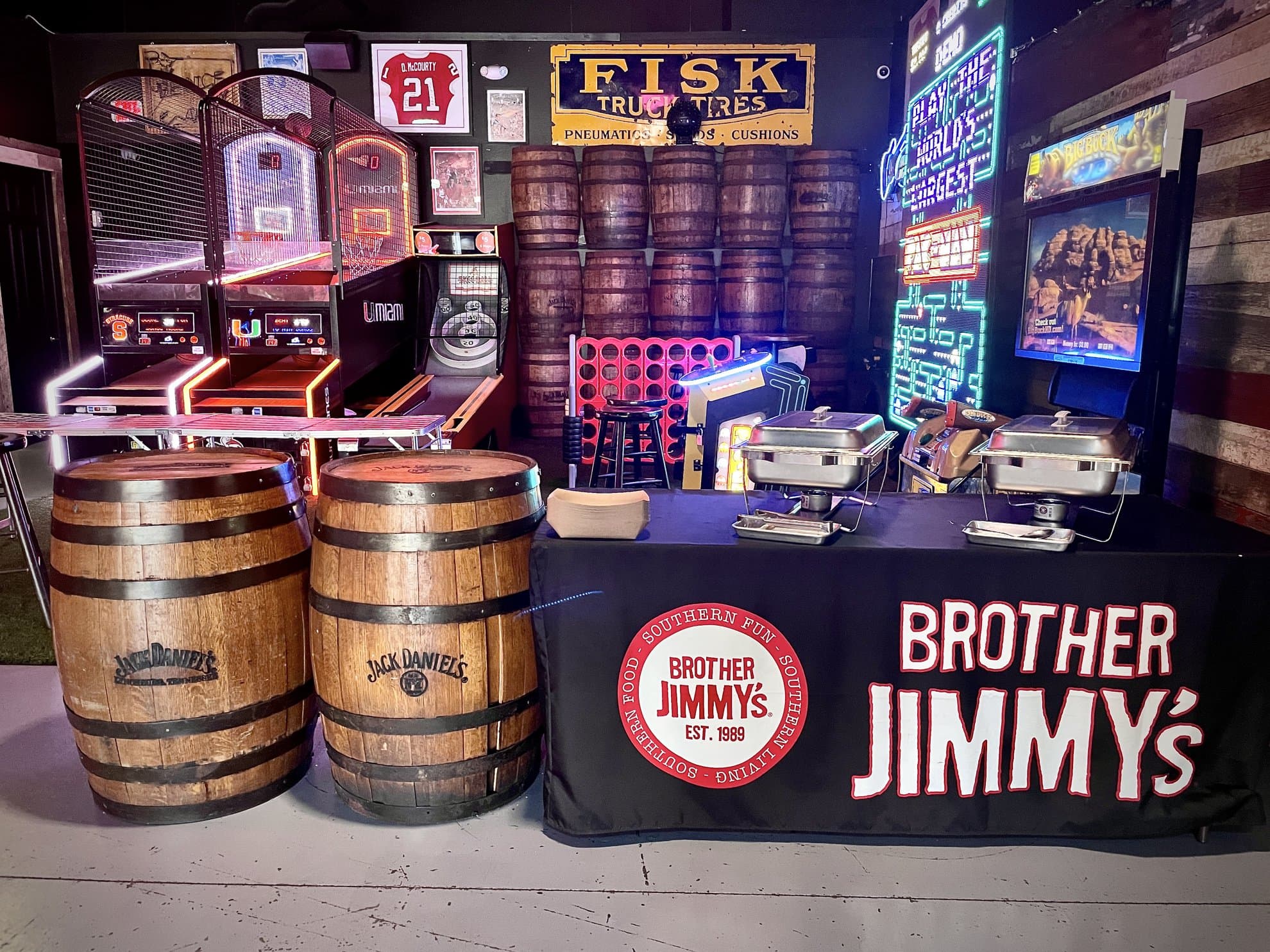 Skee-ball and arcade games in front of a wall of barrels and a Brother Jimmy's banner